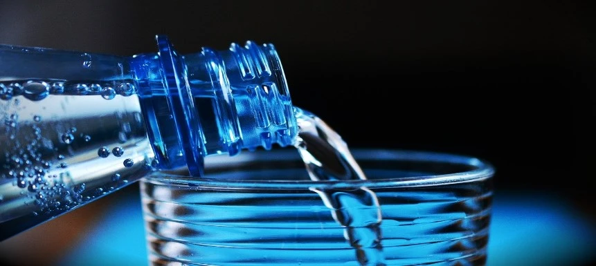 Wasser aus einer Flasche wird in ein Glas gegossen